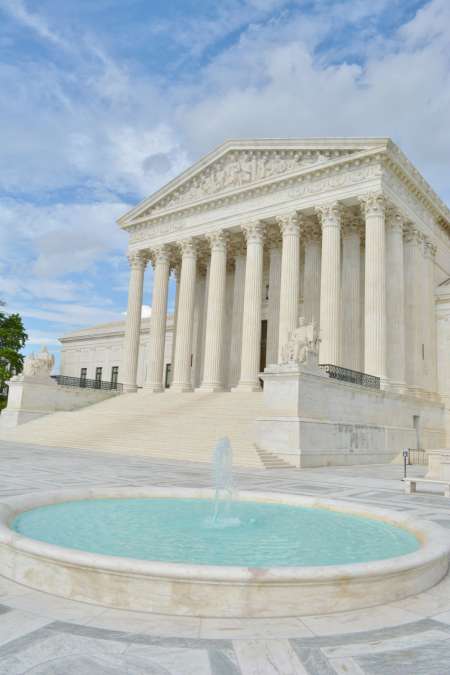 Greco-Roman, white marble facade of US Supreme Court on clear day.